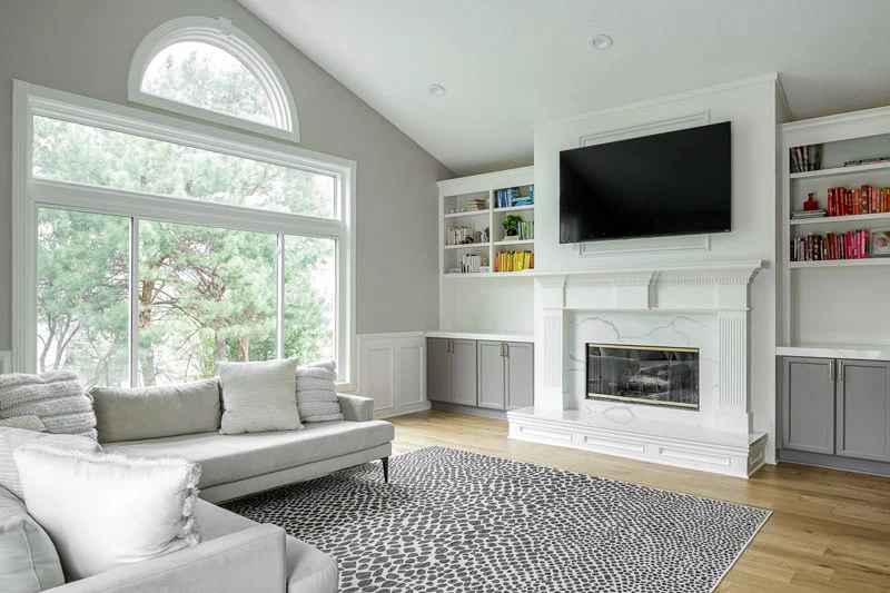 A trendy living room with white furniture and a fireplace undergoing remodeling.