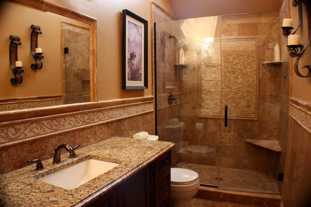 A bathroom remodel featuring a glass shower stall with brown tile.