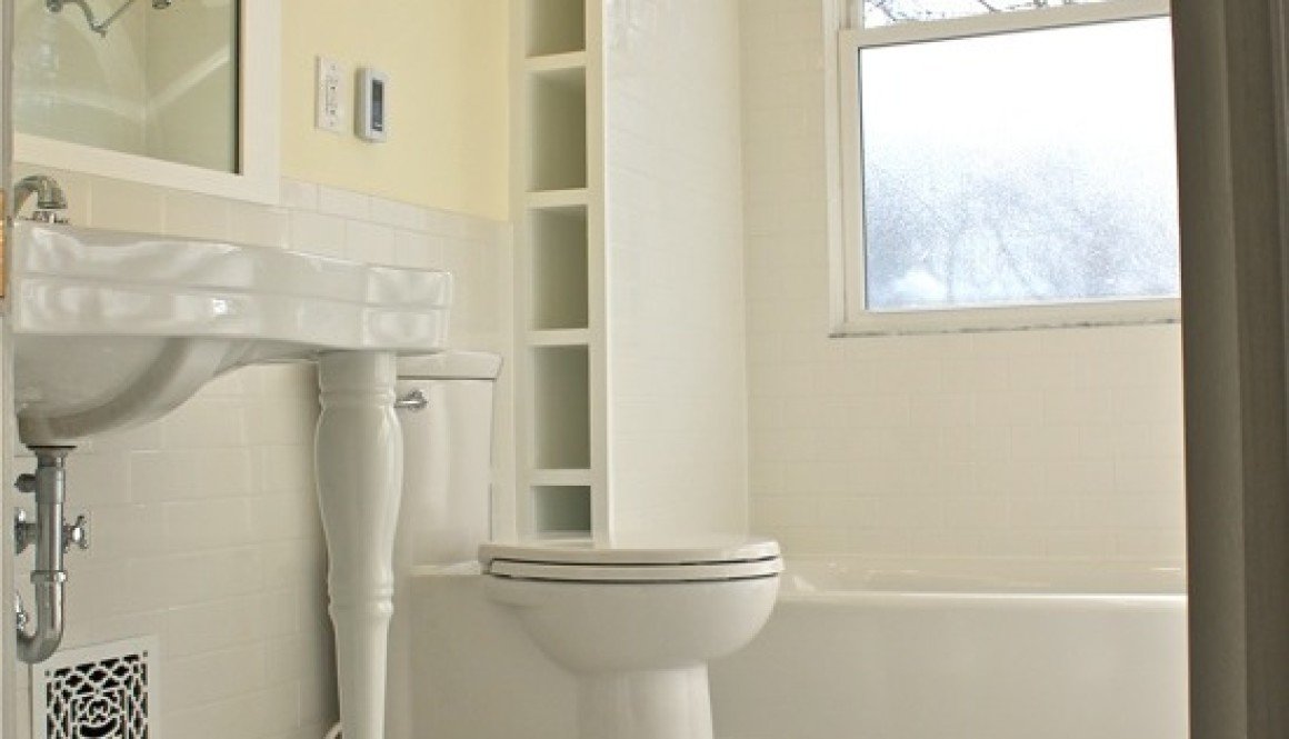 A white bathroom with a toilet and sink undergoing a bathroom remodel.