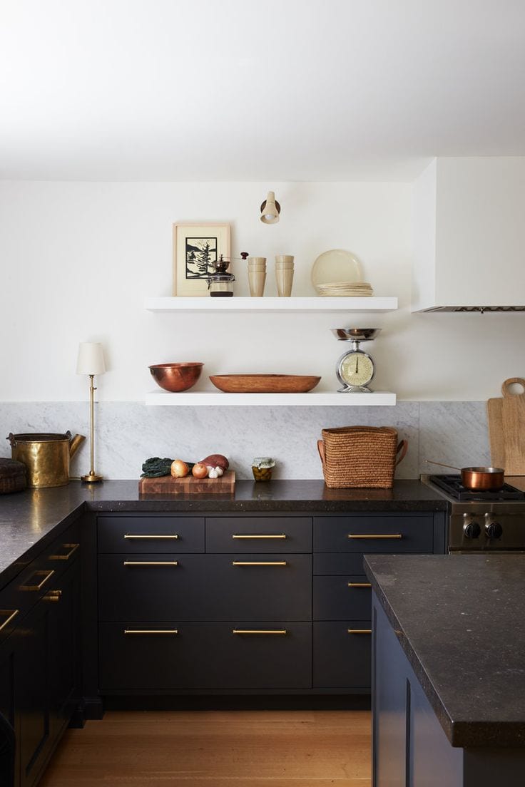 A kitchen remodel with black cabinets and gold accents.