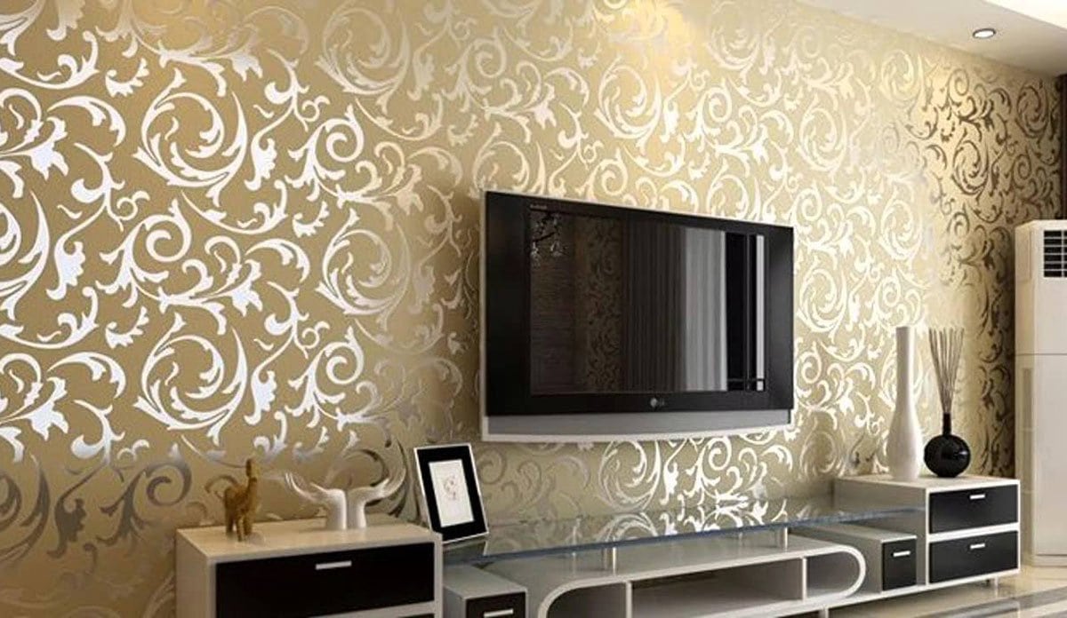 A living room with gold wallpaper undergoing a home renovation, featuring a sleek tv.