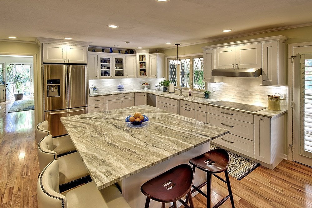 A kitchen with marble counter tops and a center island.