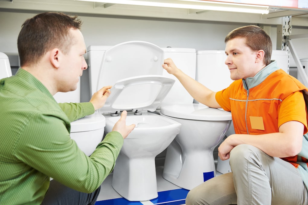 Hardware store salesperson assistant helping young man choosing toilet for bathroom remodel checklist
