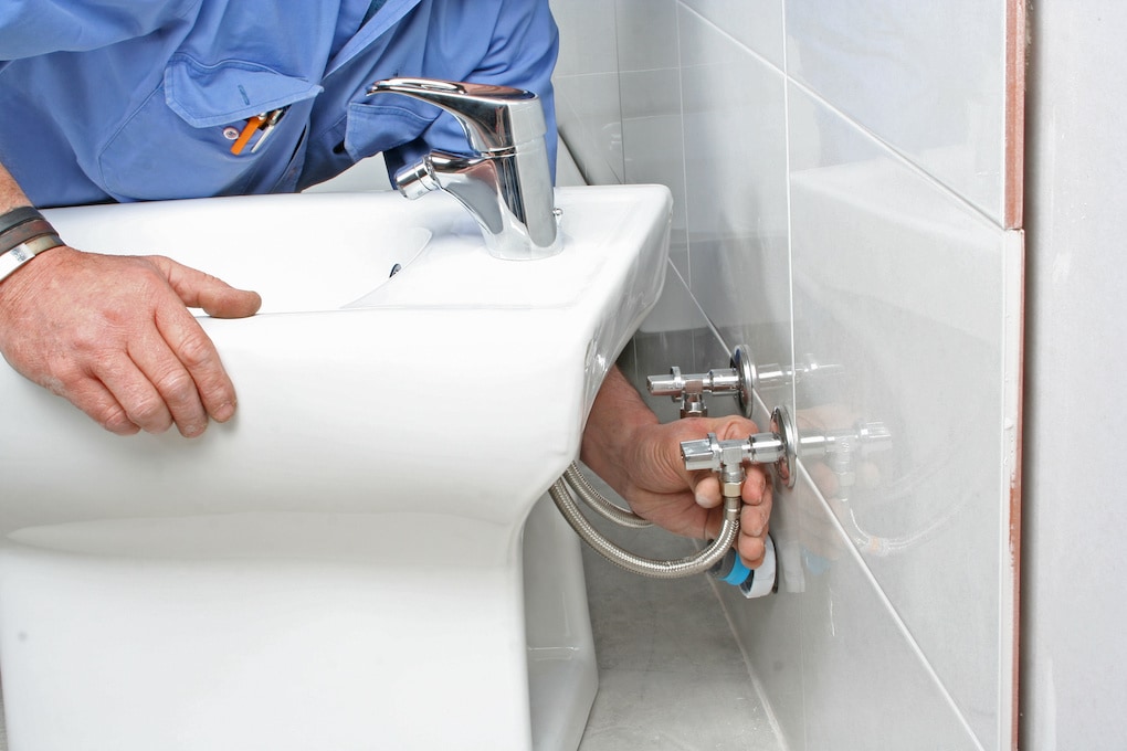 man installing plumbing in a diy bathroom remodel
