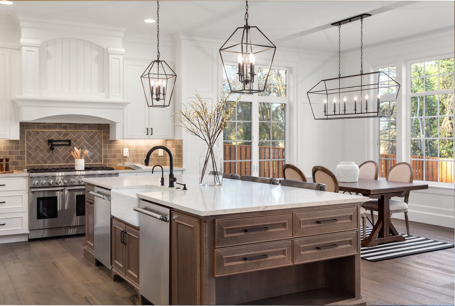 A kitchen with white cabinets and a center island, designed by Grimes.