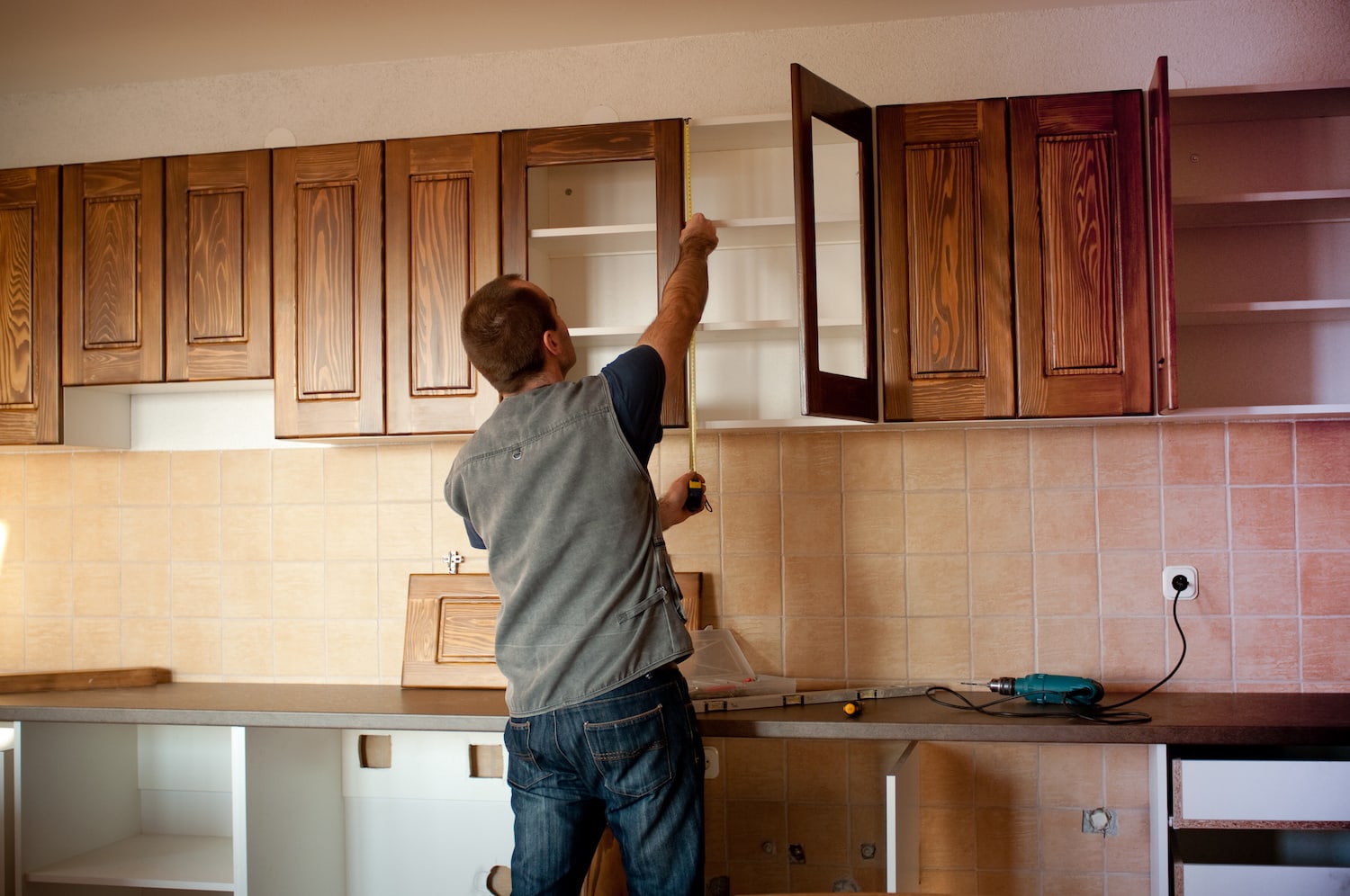 kitchen remodel contractors des moines male worker measuring old cabinets to install custom ones
