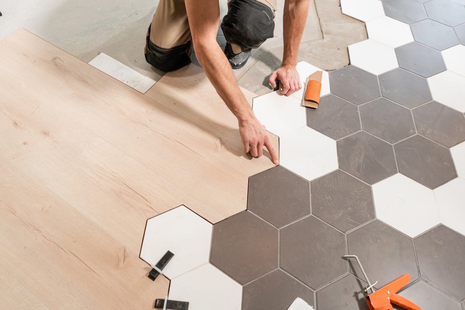 kitchen remodel contractors des moines closeup of worker installing interesting white and gray hexagon tile flooring