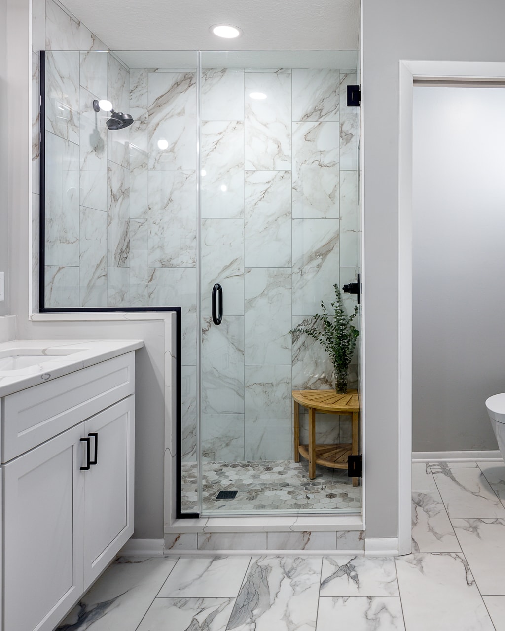 A bathroom renovation with marble floors and a walk-in shower.