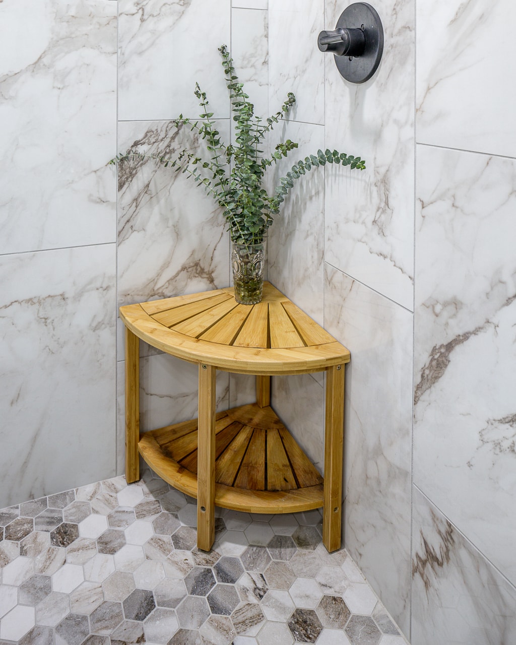 A bathroom remodel featuring a wooden shower bench and a potted plant.