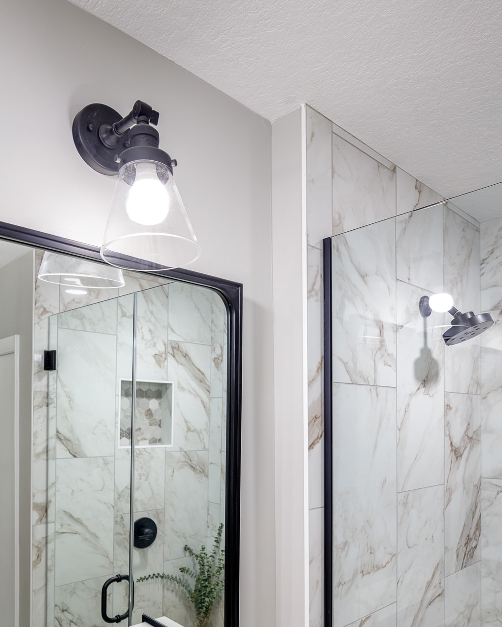 A bathroom remodel featuring a marble shower stall and mirror.