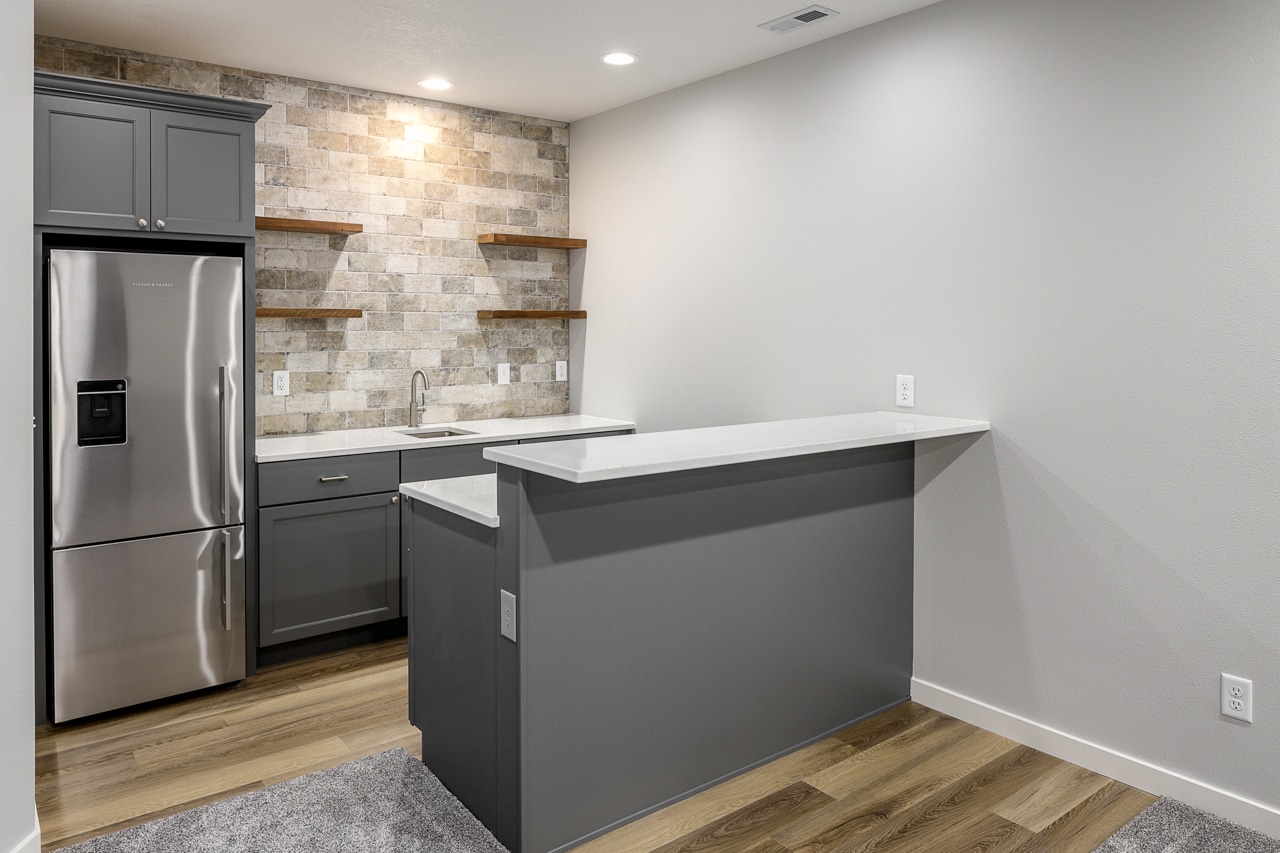 A kitchen with stainless steel appliances and wood floors in a basement remodel.