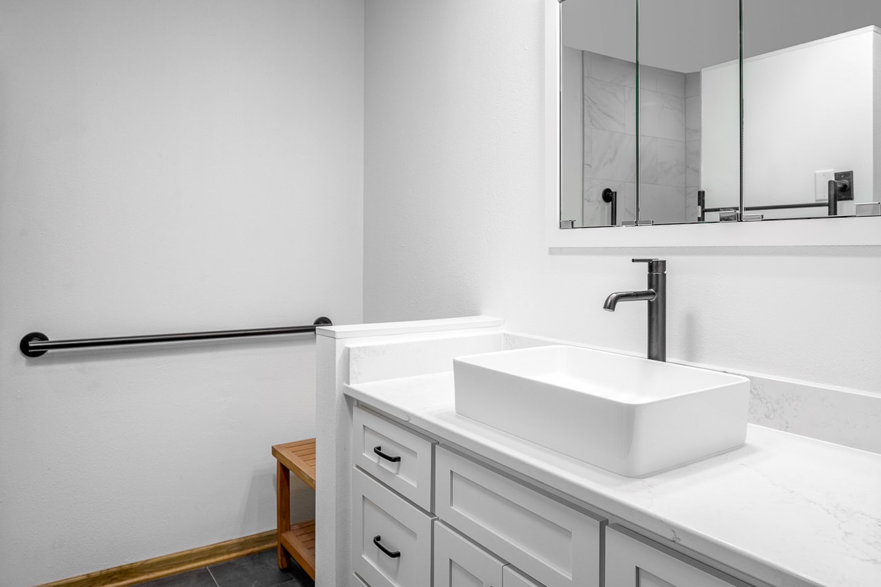 A bathroom with a white sink and mirror undergoing a home renovation.