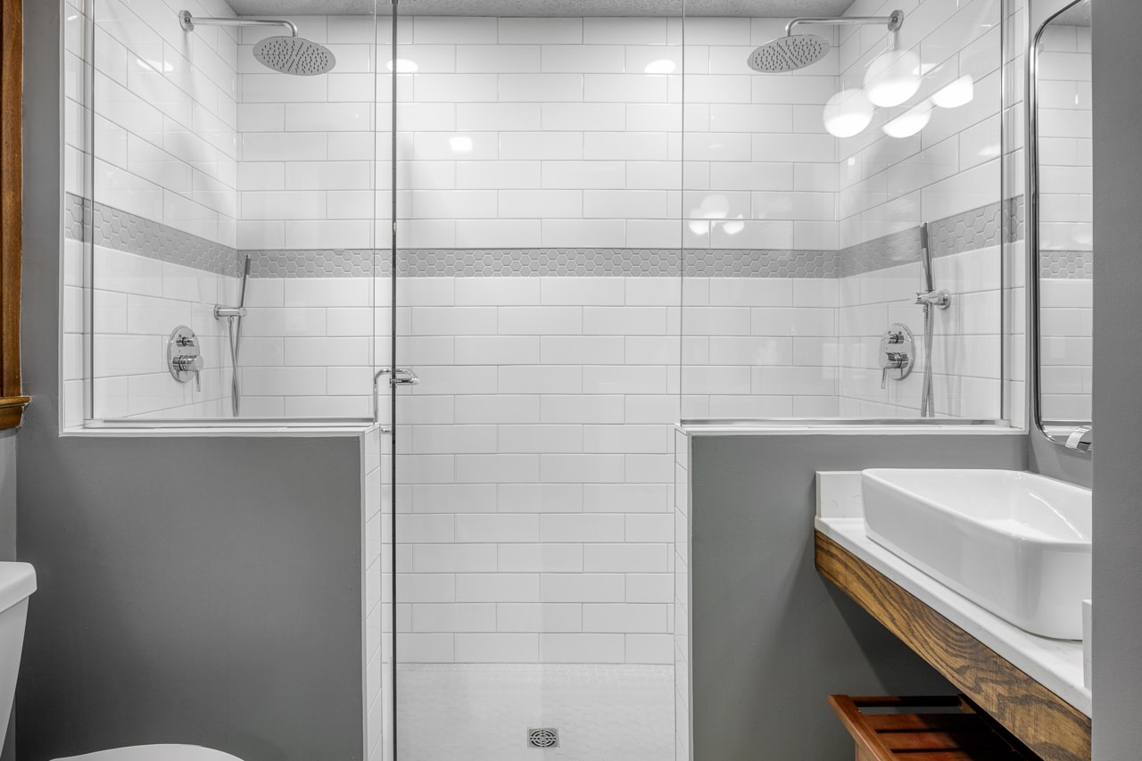 A glass shower stall and sink in a renovated bathroom.