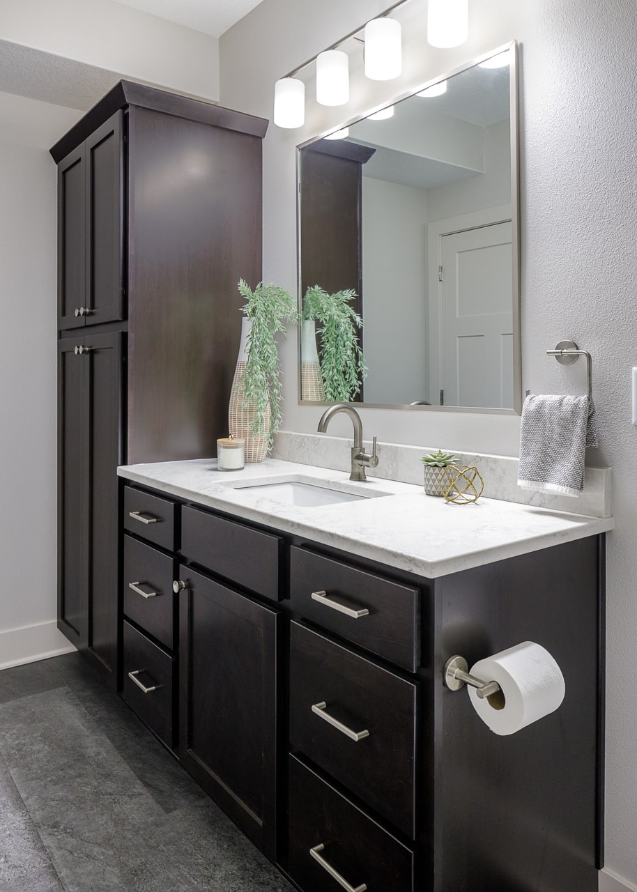 A remodeled bathroom with dark wood cabinets and a mirror.