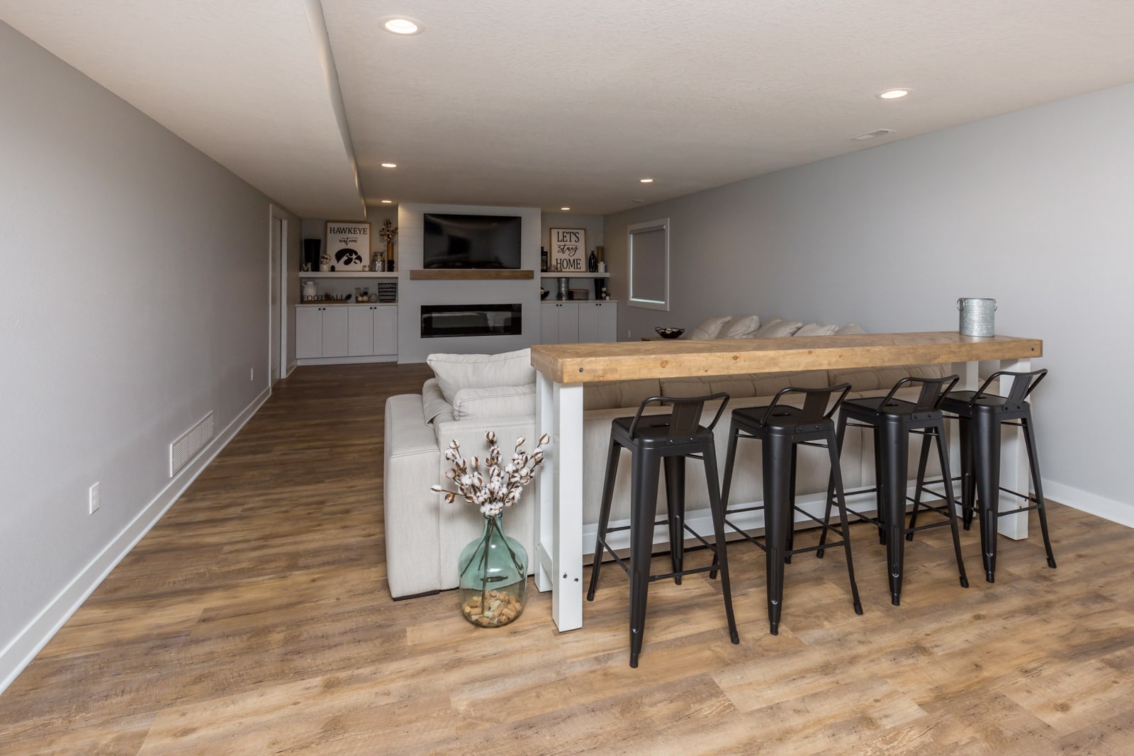 A basement with bar stools and hardwood floors.