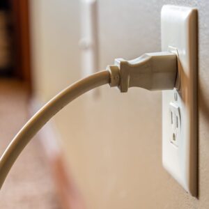 A beige electrical plug is inserted into a wall outlet, complementing the recent kitchen remodel perfectly.